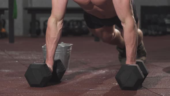 Fierce Muscular Man Doing Pushups on Dumbbells at the Gym