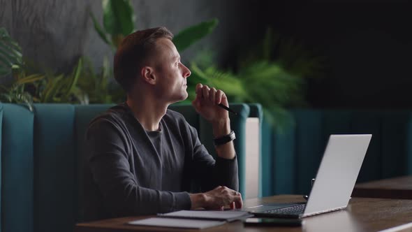 Thoughtful Serious Young Man Student Writer Sit at Home Office Desk with Laptop Thinking of