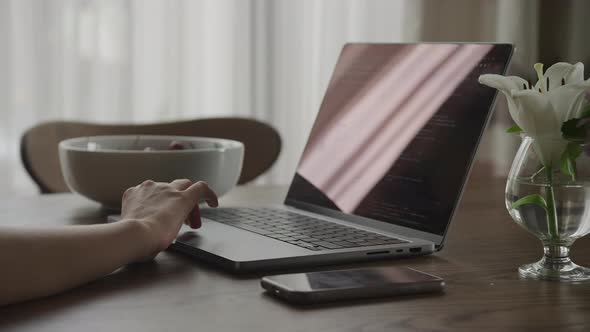 Close Up Camera Approaching a Woman Hand on a Touchpad of a Laptop Computer with Code