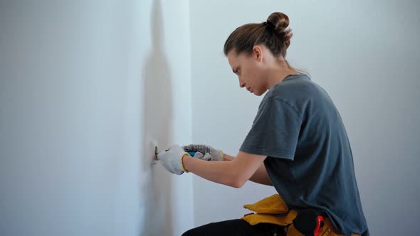 Professional Repairwoman Fixing Socket with a Screwdriver on a White Wall