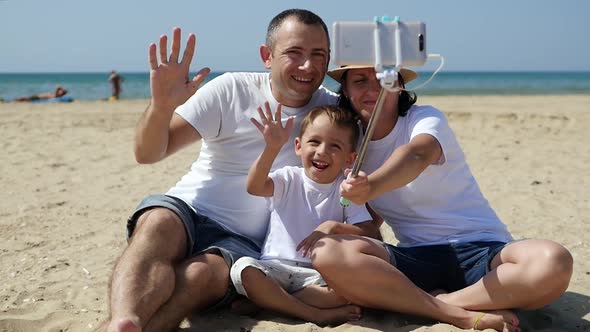 Happy Family Resting By the Sea on a Sunny Summer Day. A Man, Woman and Child Are Sitting on the