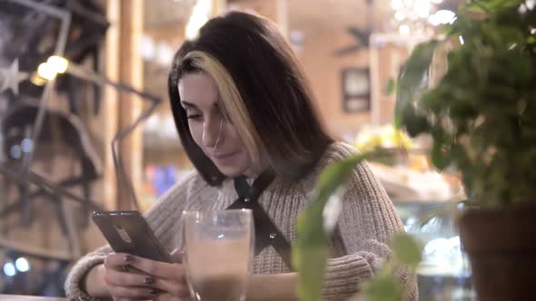 Cafe City Lifestyle Woman on Phone Drinking Coffee and Texting on Smartphone App Sitting Indoor in