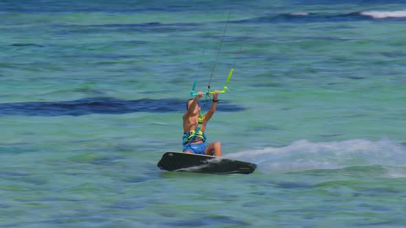 Young Kiteboarder Surfing in Mauritius Jumps While Riding Around the Turquoise Lagoon