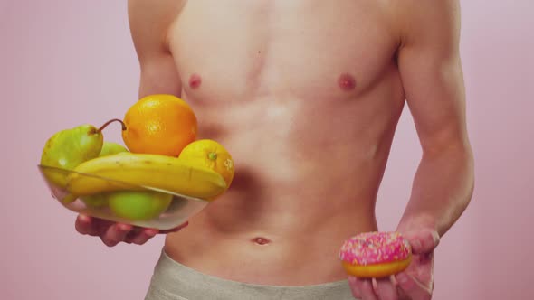 Athletic White Male Holding a Bowl of Fruits in His Right Hand and a Pink Glazed Donut in His Left