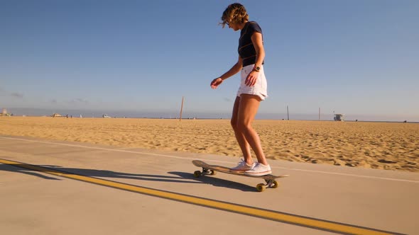 Happy Girl Turning Around While Skateboarding On Asphalt Road In Desert Park. Slow Motion