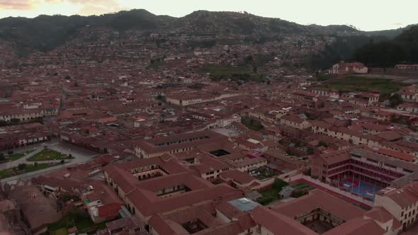 4K aerial drone view over the Plaza de Armas in Cusco at sunset. Pan right to left with a wide angle