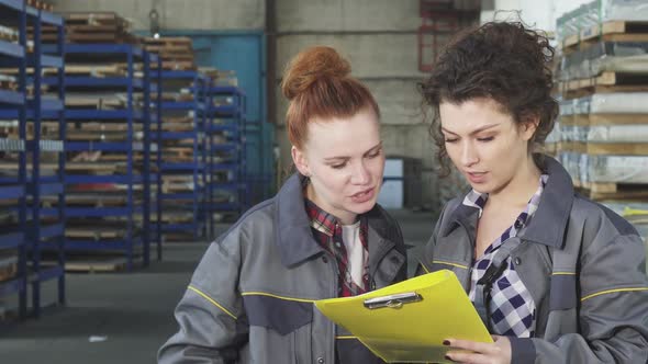 Two Female Warehouse Workers Examining Documents Together