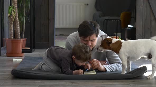 Father with a son and dog is working at home. Lying on floor