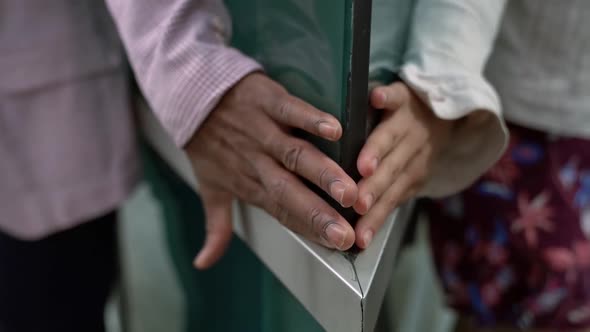 Male and Female Hands Slide Along the Glass Walls and Meet at the Corner