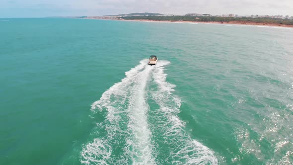 Motorboat Moving Away From The Camera In the Turquoise Sea Making Foamy Waves