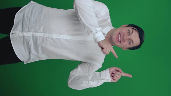 Young man in shirt dancing, having fun on a green background.