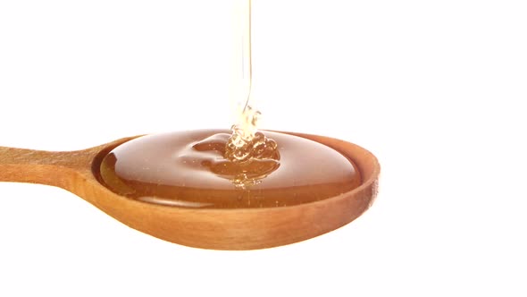 Honey Dripping From a Wooden Honey Dipper on White