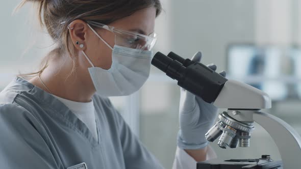 Female Scientist in Medical Uniform Using Microscope