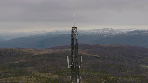 Telephone, 5G and communications tower on mountain top. View of mountain range and fjord in the back