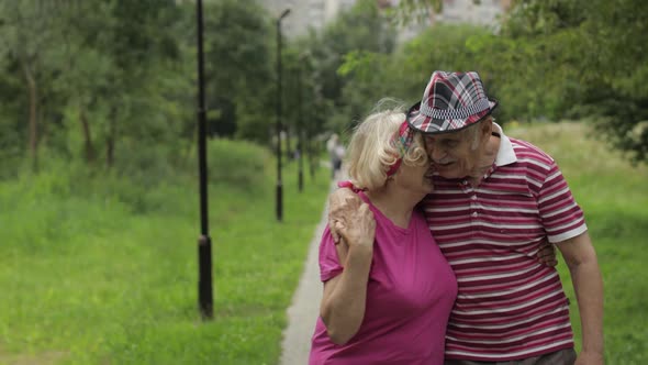 Senior Caucasian Couple Walking in Park Embracing. Elderly Man Walks with Woman. Husband, Wife