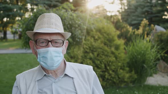 Thoughtful Senior Man with Glasses in Medical Mask Looking Sadly Into Camera