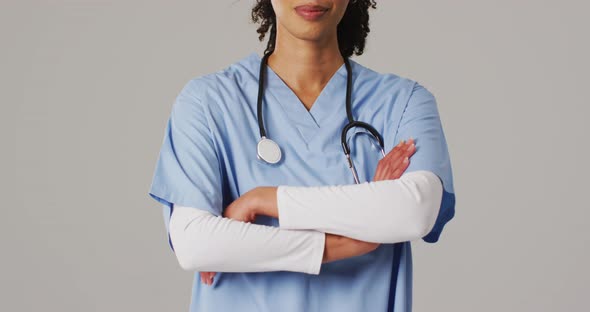 Video of smiling biracial female doctor with arms crossed on blue background