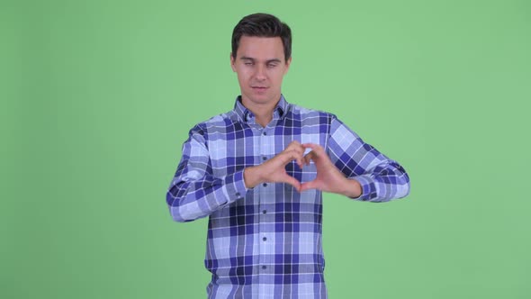 Happy Young Handsome Hipster Man with Hand Heart Gesture