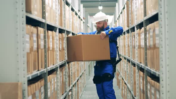 Warehouse Employee in Ergoskeleton is Displacing a Package