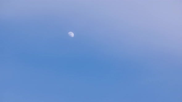 Movement of the moon over the blue sky, cloud cover, dusk timelapse