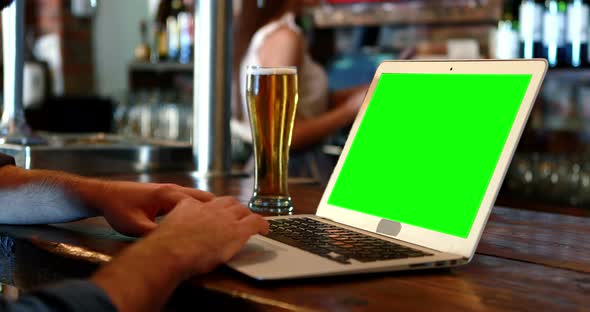 Customer using a laptop with green screen at bar counter