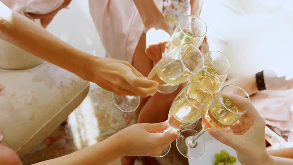 Bridesmaids in nightdress toasting a glass of champagne