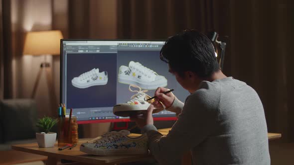 Male Footwear Designer Looking At A Desktop And Putting Coloured Unique Patterns On Sneakers