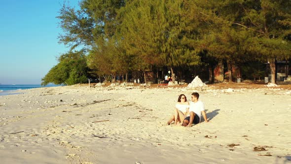 Young couple relax on relaxing sea view beach trip by blue ocean and white sandy background of Indon