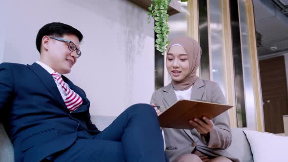 Businessman and female hijab business iscussing project at hotel lobby