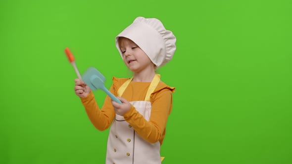 Funny Child Girl Kid Dressed Cook Chef Baker in Apron and Hat Dancing Fooling Around Making Faces