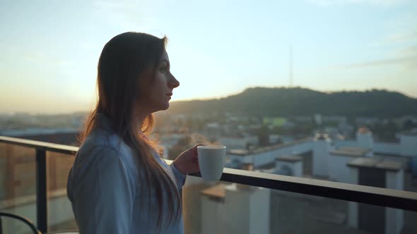 Pretty Woman Drinks Cup of Coffee or Tea, Watching a Beautiful Urban View and Enjoy Relax Breathing