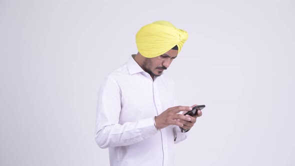 Bearded Indian Sikh Businessman Using Phone and Looking Shocked