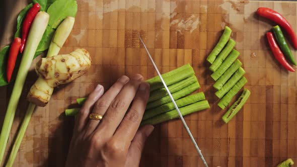 Chopping and preparing green beans on a bamboo chopping board and moving the pieces aside - Close up