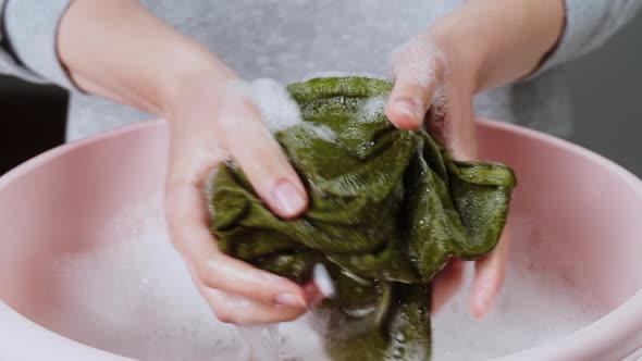 Wringing Out Green Towel in Basin with Froth and Washing Powder Closeup Using Detergent for Spoiled