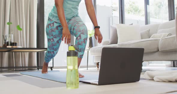 Happy african american wearing sportswear, exercising, using laptop