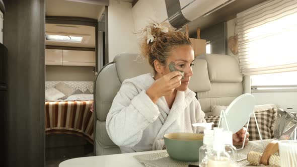 Adult woman use facial cream aging treatment inside a camper van interior during travel holiday