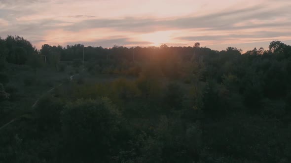 Slow aerial flight over a tree towards a highway outside nepean city, ontario at sunset with the sun