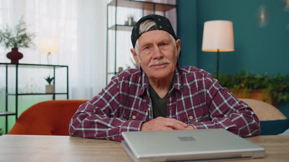 Senior Grandfather Man Using Laptop Computer Typing at Home Room Looking at Camera Smiling