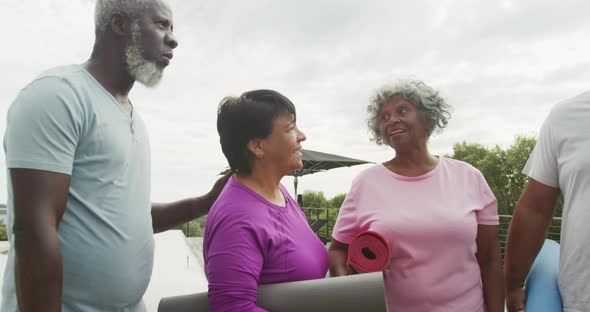 Happy senior diverse people practicing yoga in garden at retirement home