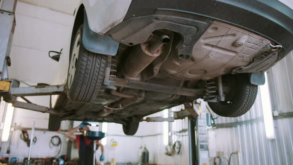 Auto Mechanic Repairs Car on the Lift in the Service Station