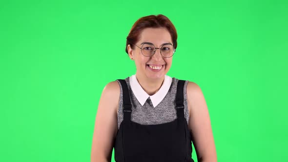 Portrait of Funny Girl in Round Glasses Is Shyly Saying Wow and Tender Smiling. Green Screen