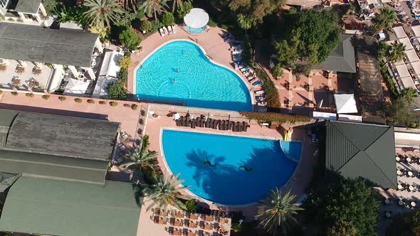 Aerial drone shot of hotel gardens and swimming pools at a sunny resort.