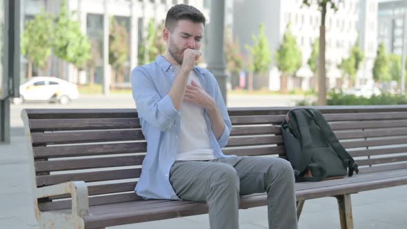 Young Man Coughing While Sitting on Bench