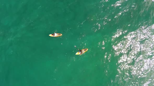 Aerial view of two men sup stand-up paddleboard surfing in Hawaii