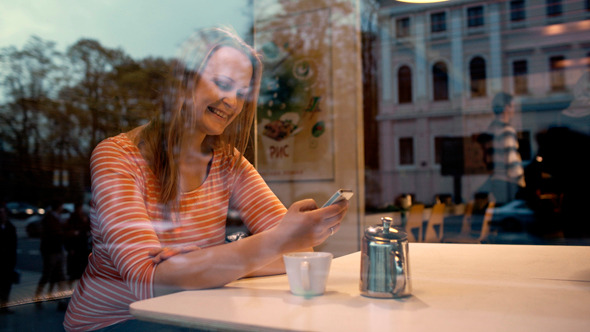 Woman With Phone In Cafe Enjoying Outside View