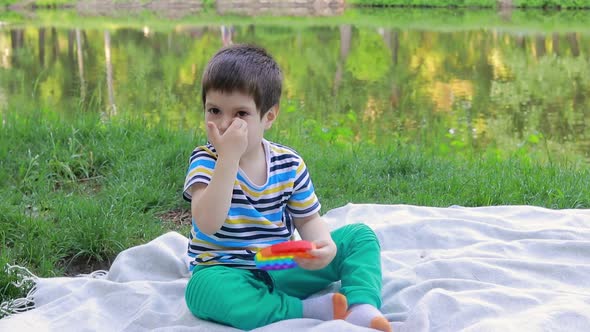 A Baby Boy of 4 Years Plays with Pop It in Nature