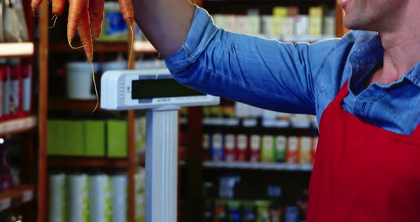 Smiling staff holding bunch of carrots in organic section