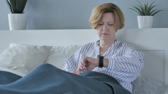 Waiting Old Senior Woman Watching Time while Sitting in Bed