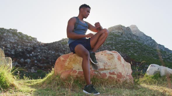 African american man cross country running sitting on rock in mountain countryside