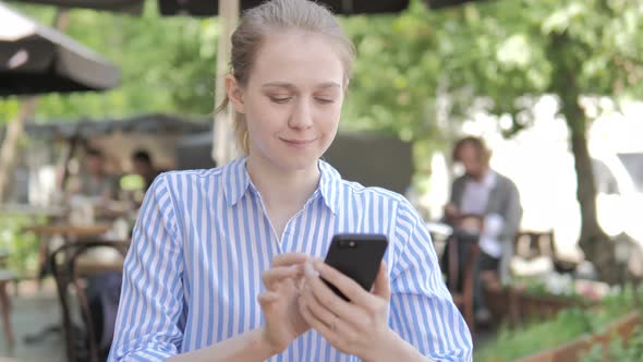 Young Woman Using Smartphone Sitting in Cafe Terrace